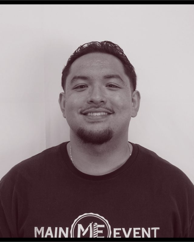 Portrait of barber DeAngelo “Delo” Cabuloy, smiling, in a black Main Event T-shirt